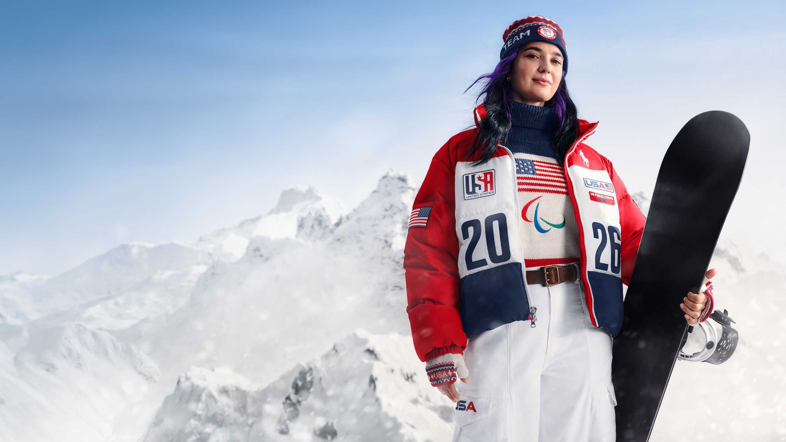 athlete holding a snowboard in a snowy mountain setting