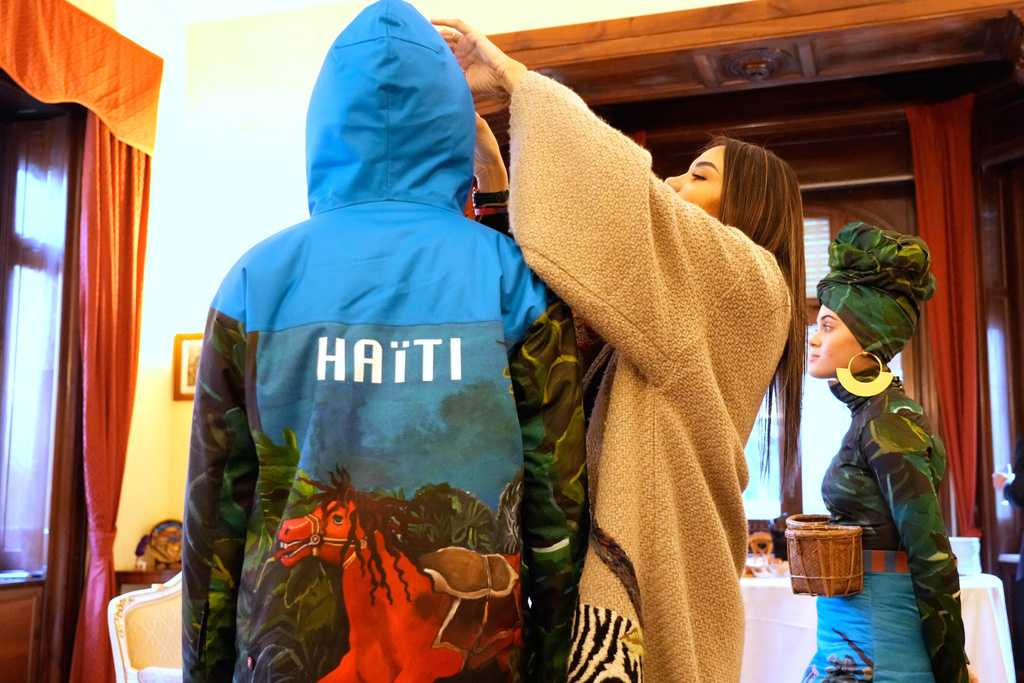 Italian-Haitian designer Stella Jean, center, helps Megan Thomas, left, and Livia Audain at the Haitian Embassy in Rome, Saturday, Jan. 31, 2026, wear the official uniform of the Haitian national team participating in the 2026 Winter Olympics. (AP Photo/Gregorio Borgia)