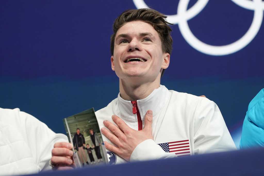 Maxim Naumov of the United States waits for his scores while holding a photo of his parents after competing during the men&amp;apos;s figure skating short program at the 2026 Winter Olympics, in Milan, Italy, Tuesday, Feb. 10, 2026. (AP Photo/Francisco Seco)
