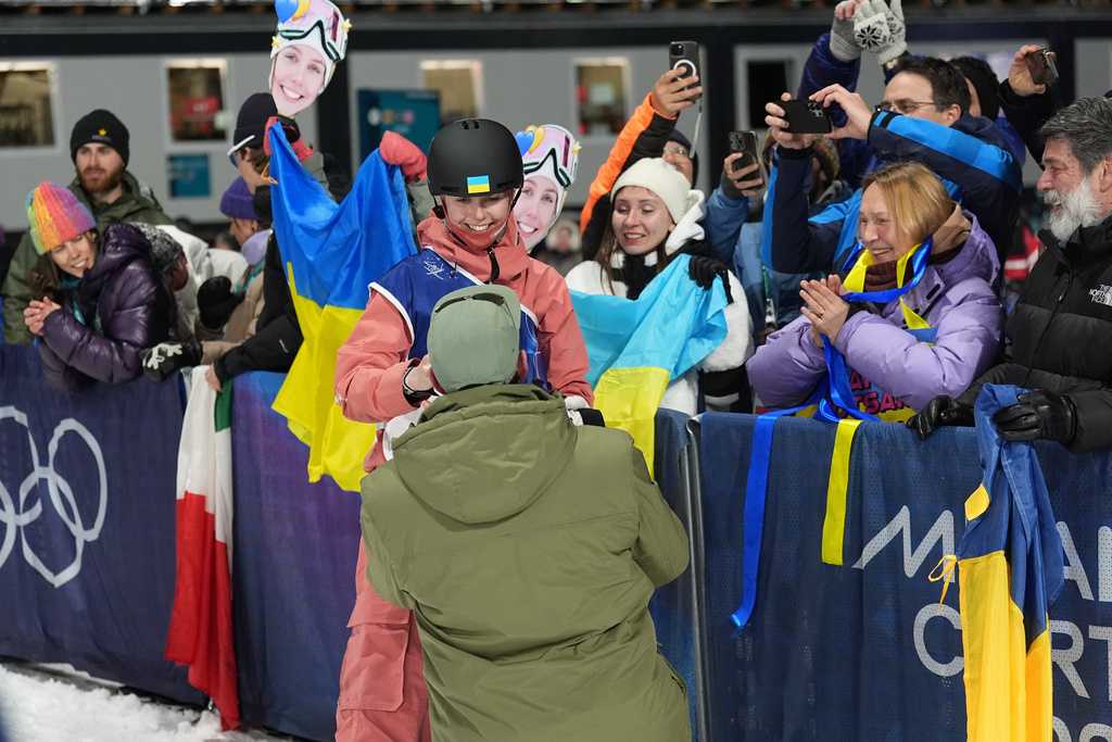 Ukraine&amp;apos;s Kateryna Kotsar gets a proposal from Bogdan Fashtryga, front, as she competes in the women&amp;apos;s freestyle skiing big air qualifications at the 2026 Winter Olympics, in Livigno, Italy, Saturday, Feb. 14, 2026. (AP Photo/Abbie Parr)