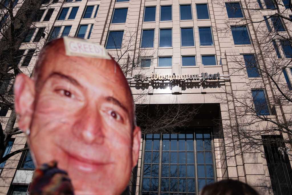 A protester holds a cutout of Jeff Bezos&amp;apos; face outside of the Washington Post office following a mass layoff, Thursday, Feb. 5, 2026.