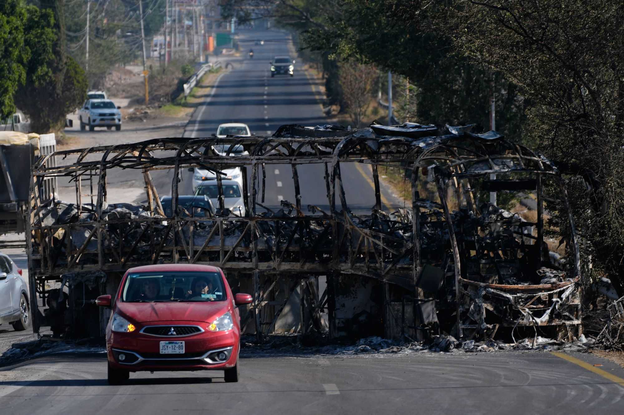 Vehicles drive past a charred bus the day after the Mexican army killed Jalisco New Generation Cartel leader Nemesio Oseguera Cervantes, known as "El Mencho," in Guadalajara, Mexico, Monday, February 23.
