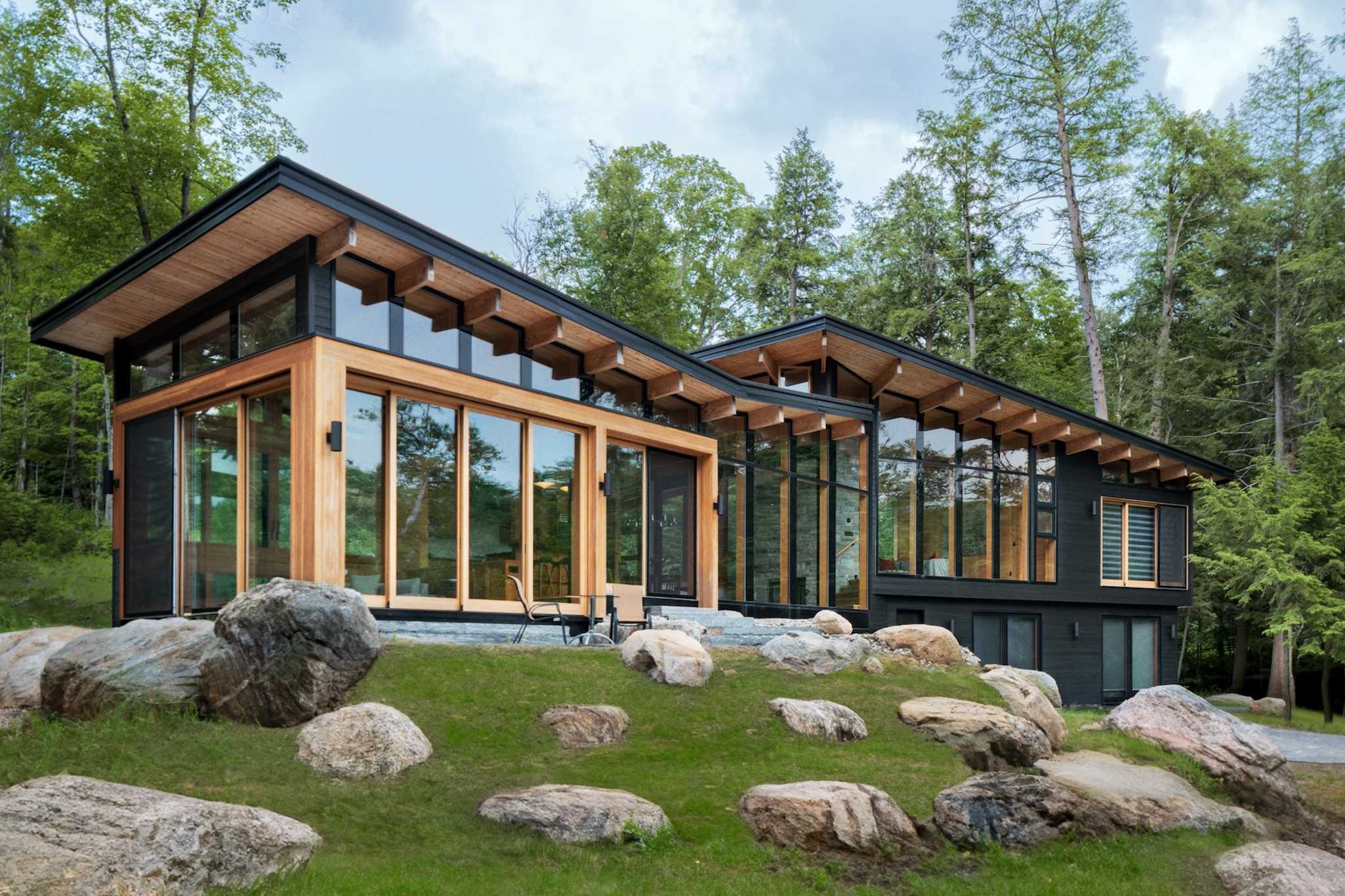 Modern house with large windows and wooden details surrounded by greenery.