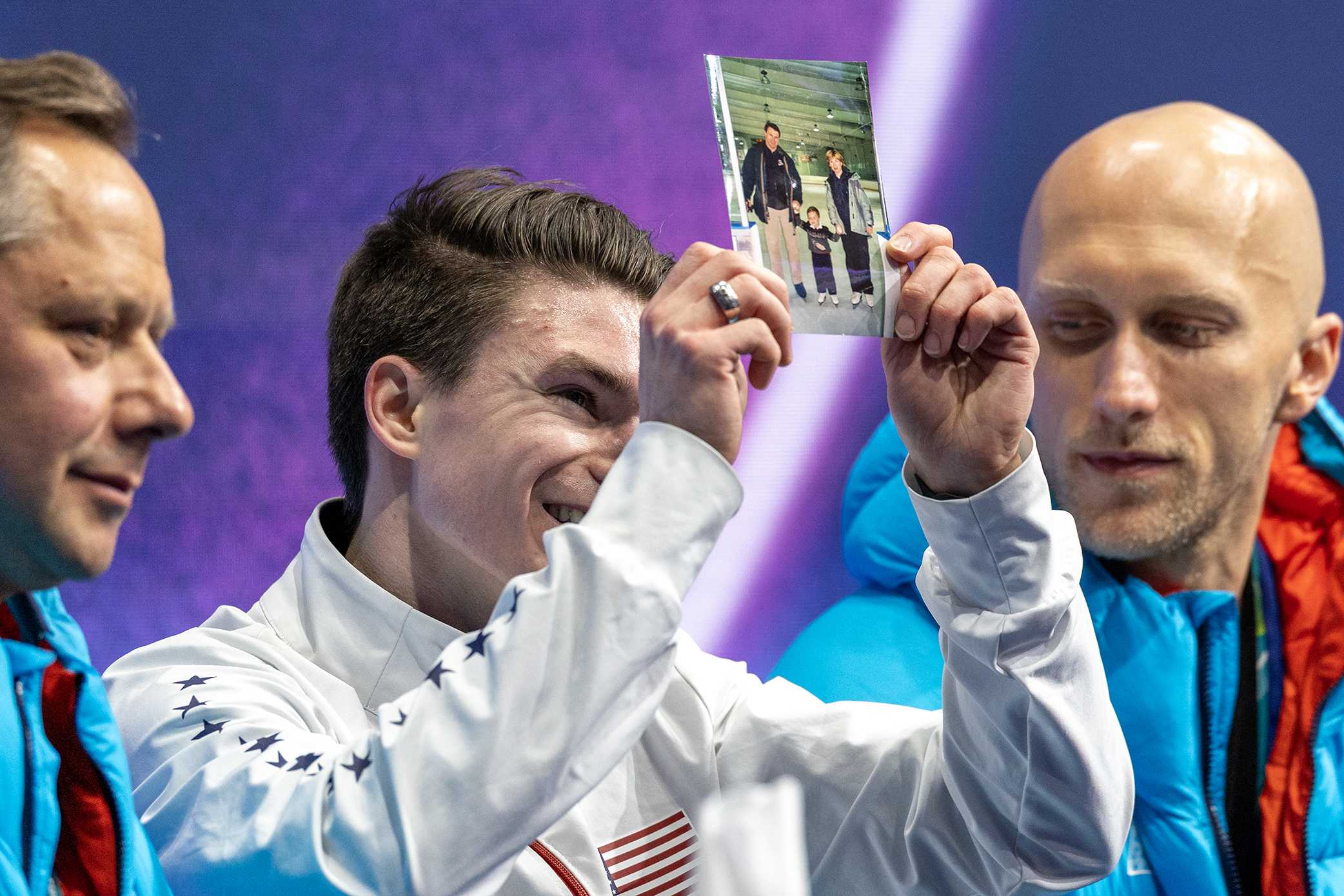 Maxim Naumov of the United States with a picture of his parents as he awaits his score after performing his routine during the Figure Skating, Men's Singles Skating-Free Skating competition at the Milano Ice Skating Arena at the Milano Cortina Winter Olympic Games 2026 on Feb. 13, 2026, in Milan, Italy.