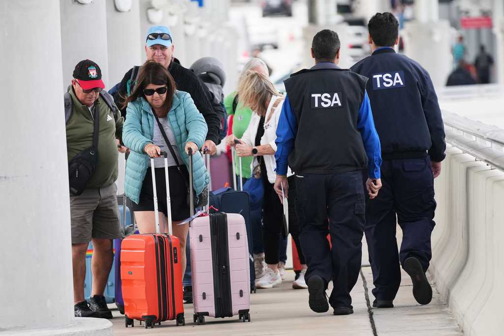 FILE - Travelers walk with their luggage past TSA agents at Fort Lauderdale-Hollywood International Airport, Nov. 13, 2025, in Fort Lauderdale, Fla.
