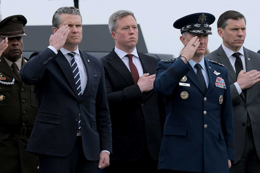 DOVER, DELAWARE - MARCH 07: (L-R) U.S. Secretary of War Pete Hegseth, U.S. Secretary of the Army Daniel Driscoll and Chairman of the Joint Chiefs of Staff Gen. Dan Caine stand at attention as U.S. Army carry teams move flagged-draped transfer cases at Dover Air Force Base March 07, 2026 in Dover, Delaware.  Six soldiers from the 103rd Sustainment Command were killed in action by an Iranian drone strike on March 1 in Port Shuabia, Kuwait during &amp;quot;Operation Epic Fury&amp;quot;.  (Photo by Anna Moneymaker/Getty Images)