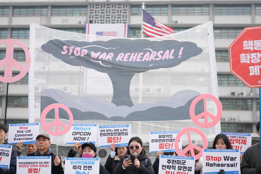 Protesters hold signs to oppose the joint military exercise between the U.S. and South Korea, near the U.S. Embassy in Seoul, South Korea, Monday, March 9, 2026.
