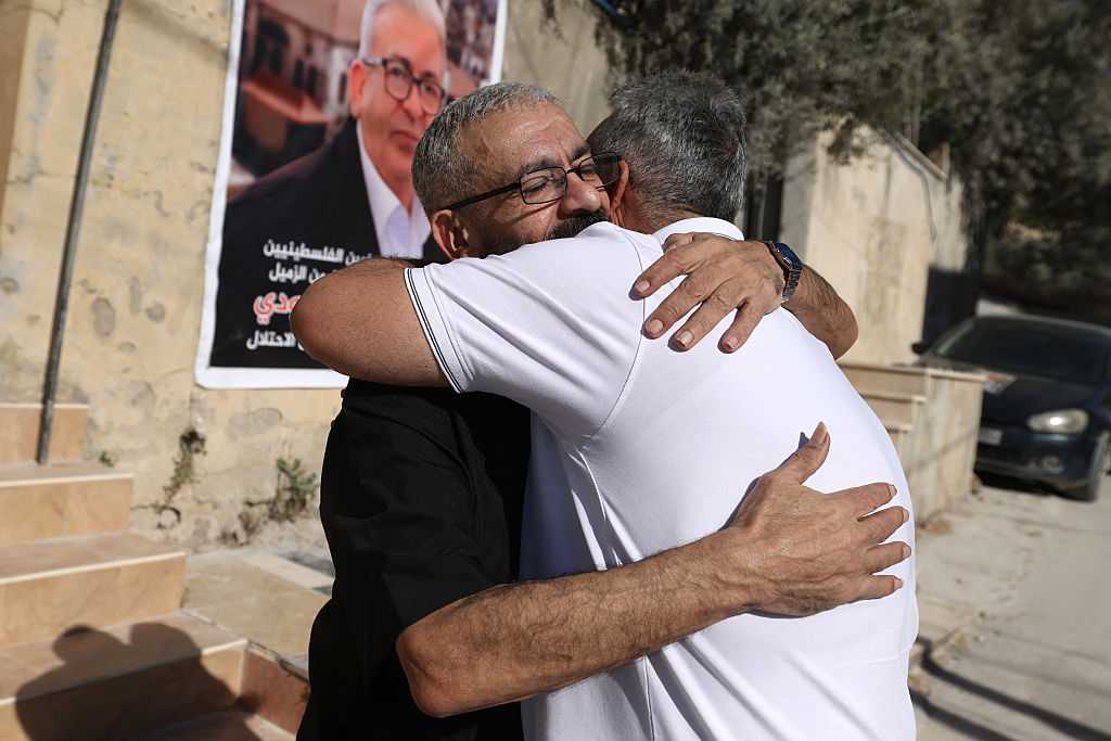 Palestinian journalist Ali al-Samoudi is hugged by a relative as he stands in front of a large image of himself taken before he was detained by the Israeli army and held for a year, at his home in the northern city of Jenin, in the Israeli-occupied Palestinian West Bank on May 1, 2026. Sixty-year-old Al-Samoudi was released following one-year in detention in the Israeli Naqab Prison, located in southern Israel. He was released and checked at the Jenin Hospital where he said, &amp;quot;I was 120 kilogrammes; my weight now is barely 60 kilogrammes&amp;quot;. Israel has jailed an increasing number of journalists since 2023, the year of Hamas&amp;apos;s unprecedented October 7 attack on Israel, which responded with a devastating war in the Gaza Strip. (Photo by JAAFAR ASHTIYEH / AFP via Getty Images)